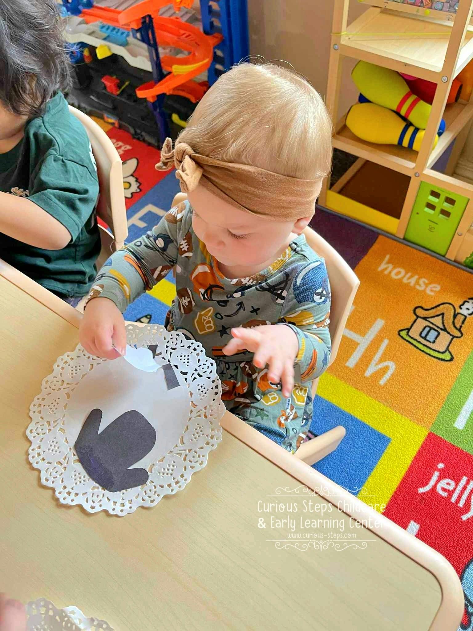 Child at a table playing with a paper doily and a cutout shape