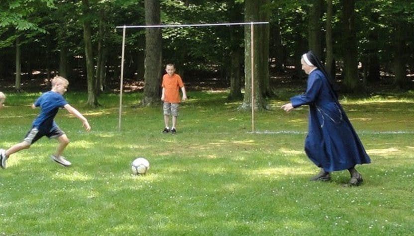 Person in habit playing soccer with two children