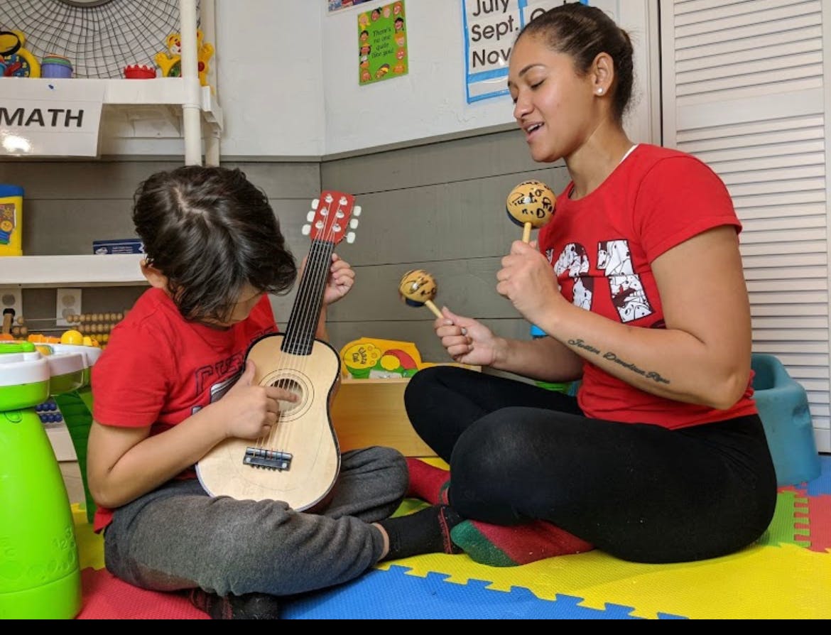 Person playing maracas and child playing a toy guitar