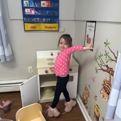 Child standing next to a toy kitchen set