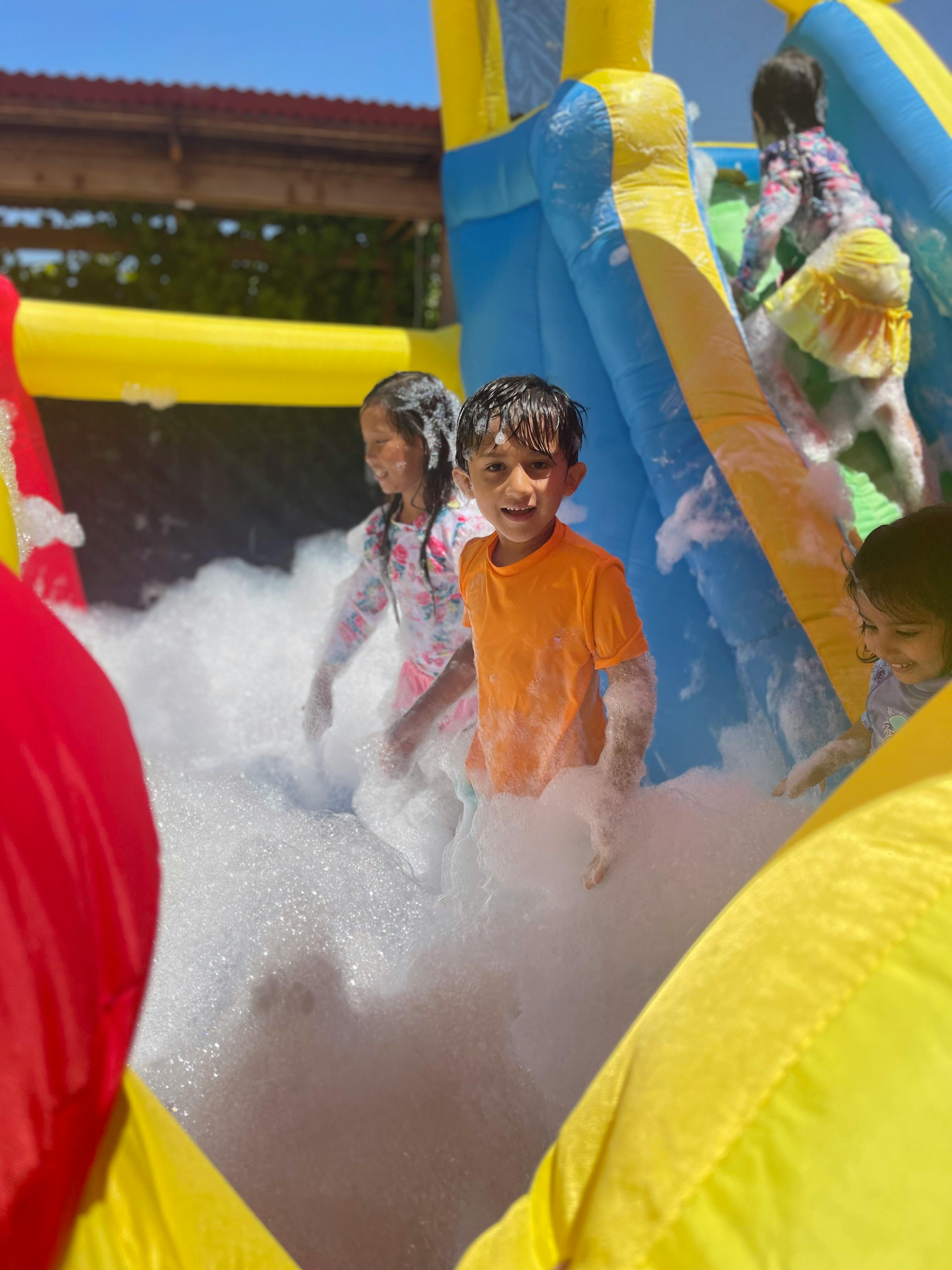 Children playing in foam on an inflatable slide