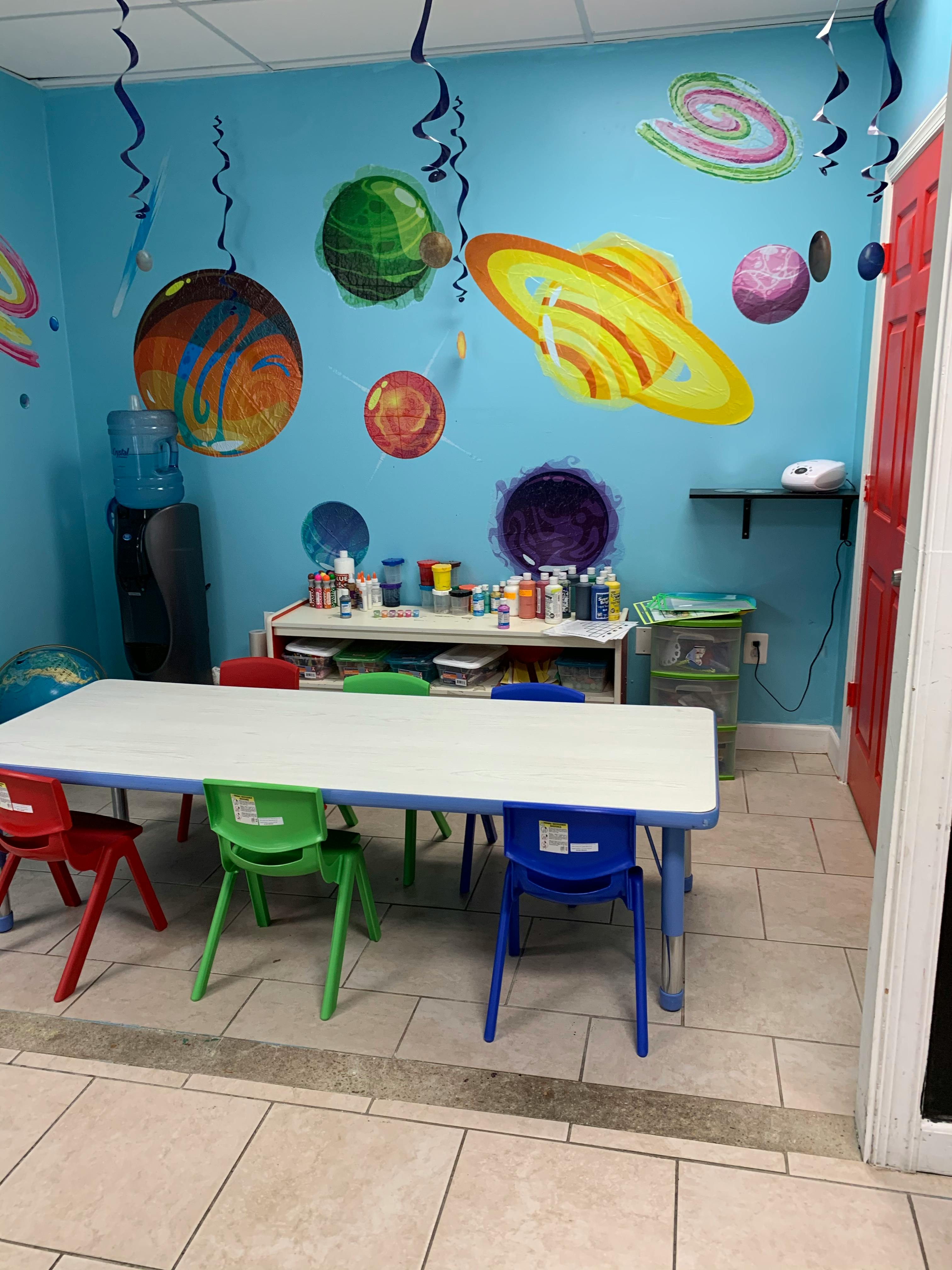 Classroom with a long table and chairs, space-themed wall decorations
