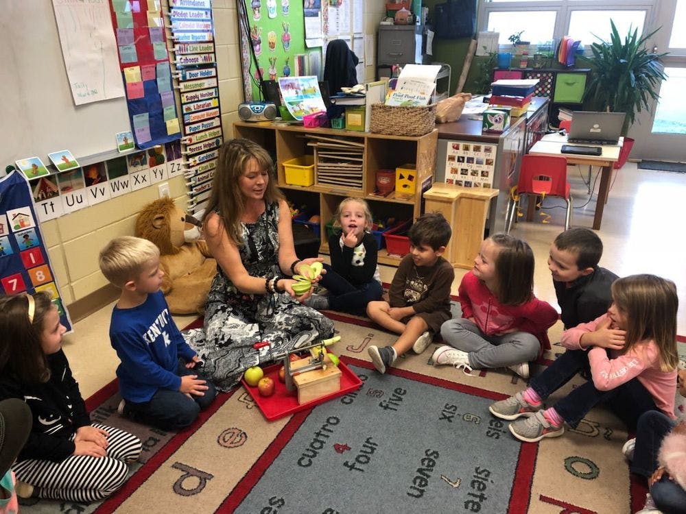 Adult and children sitting on a rug in a classroom