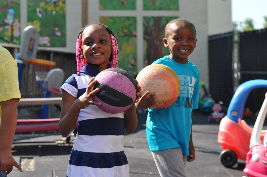 Two children holding balls on a playground