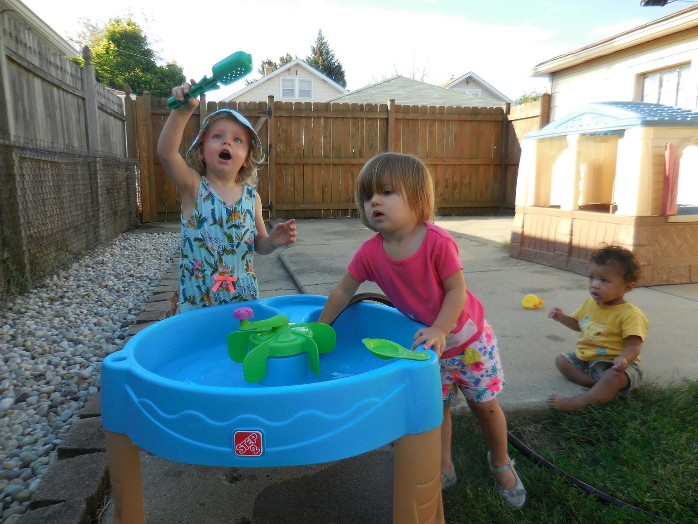 Three children playing with a water table outdoors