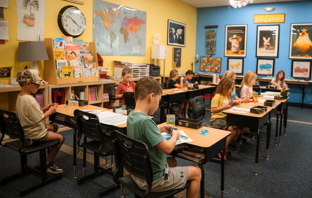 Children working on craft projects at desks in a classroom