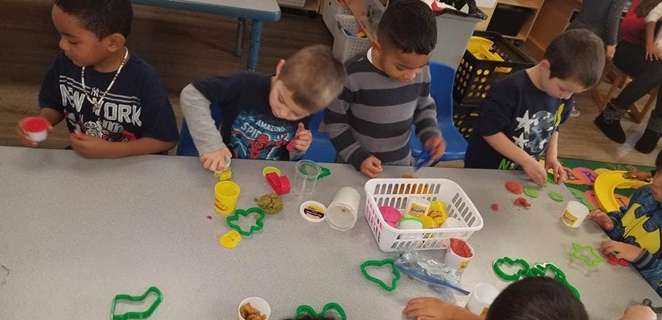 Children playing with modeling clay and cookie cutters at a table