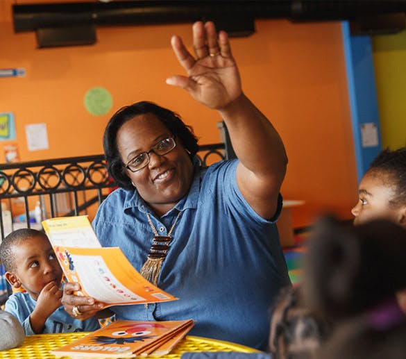 Person reading to children, one child looking up at the person