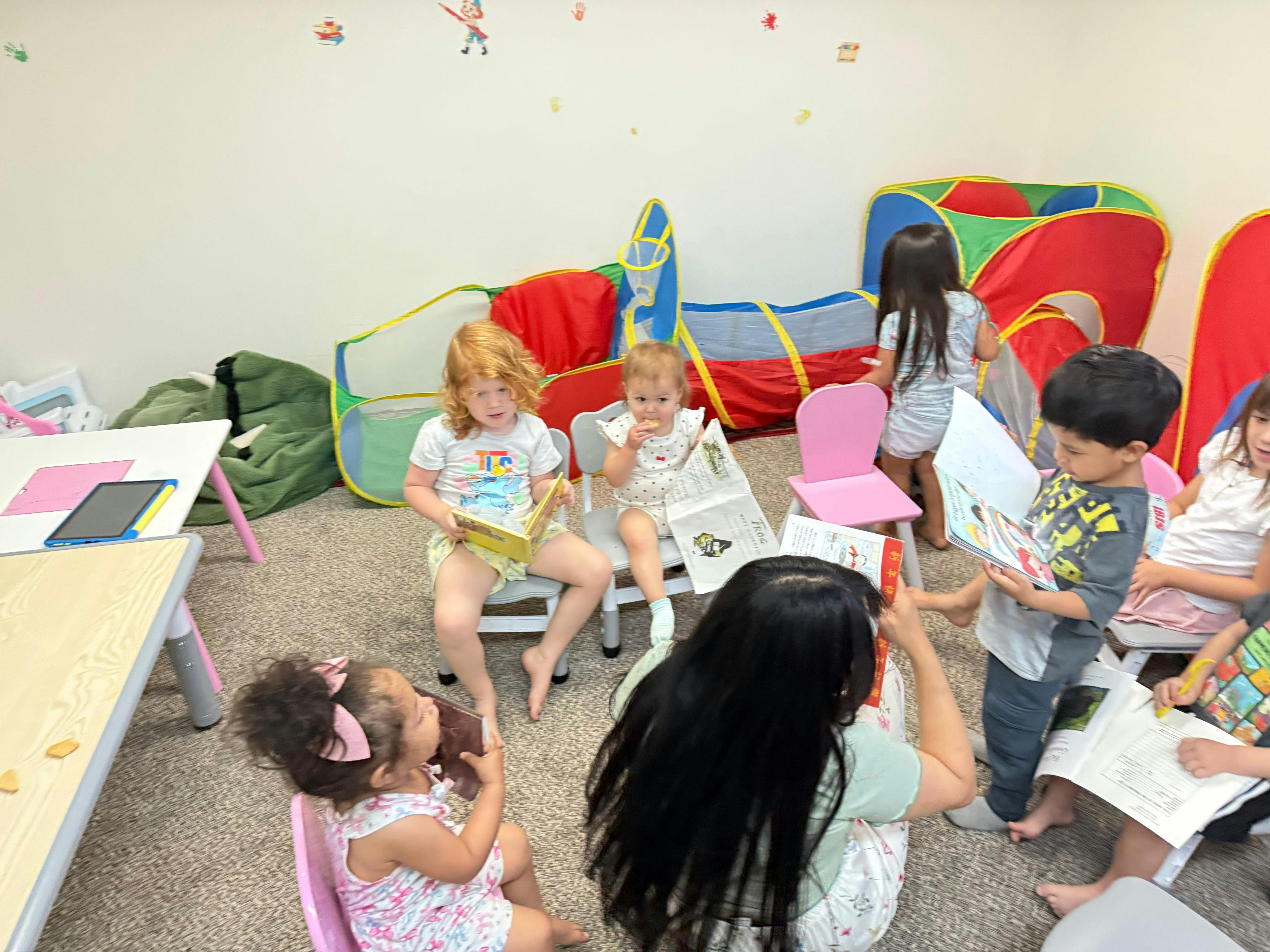 Children reading books with an adult in a playroom