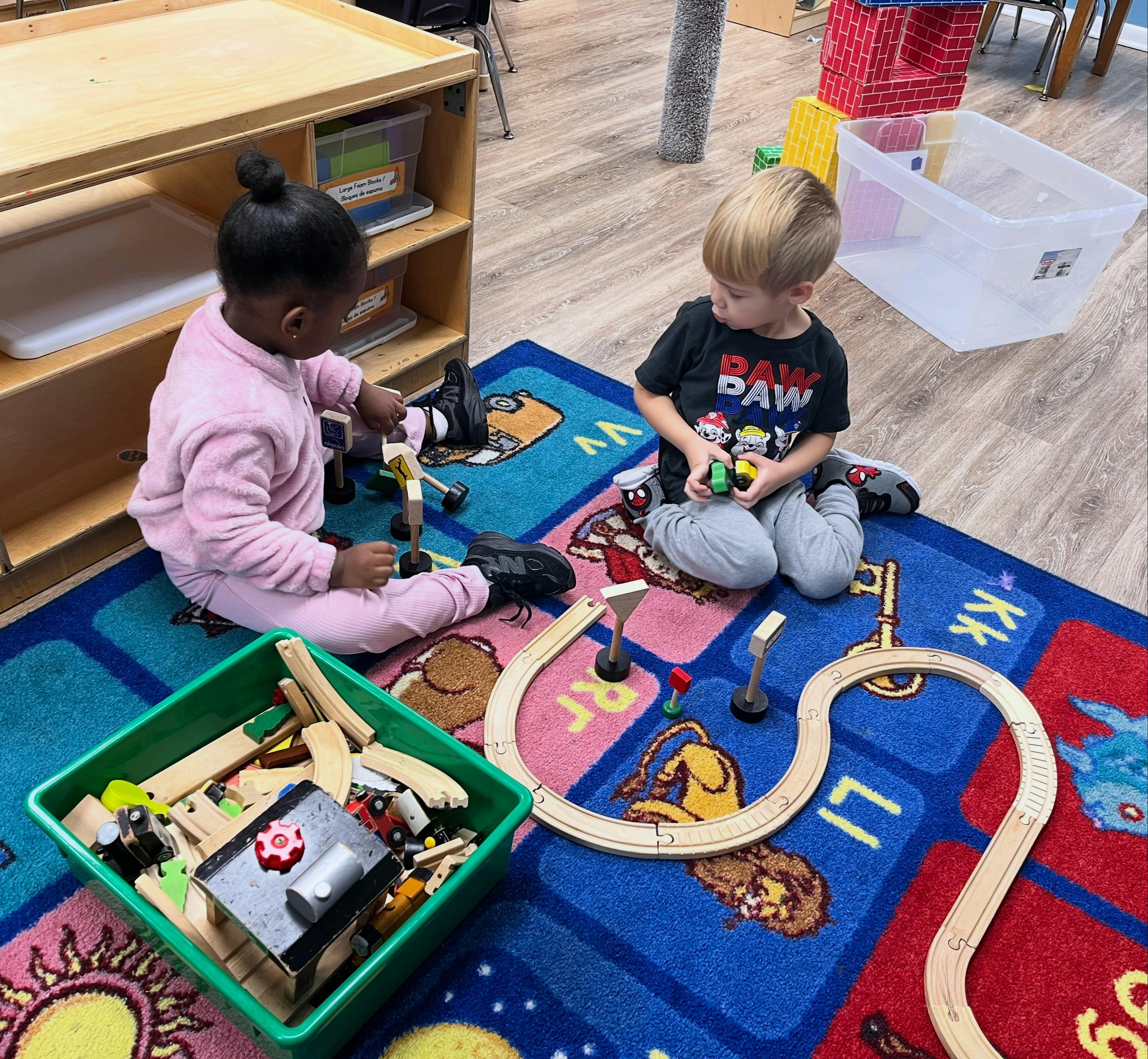 Two children playing with toys on a colorful rug