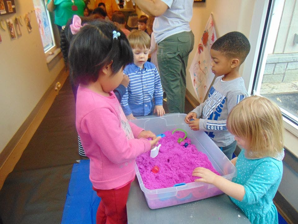 Children playing with kinetic sand in a container