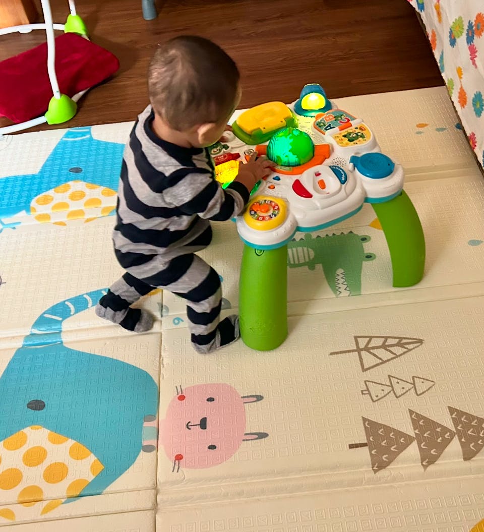 Child in striped pajamas playing with an activity table