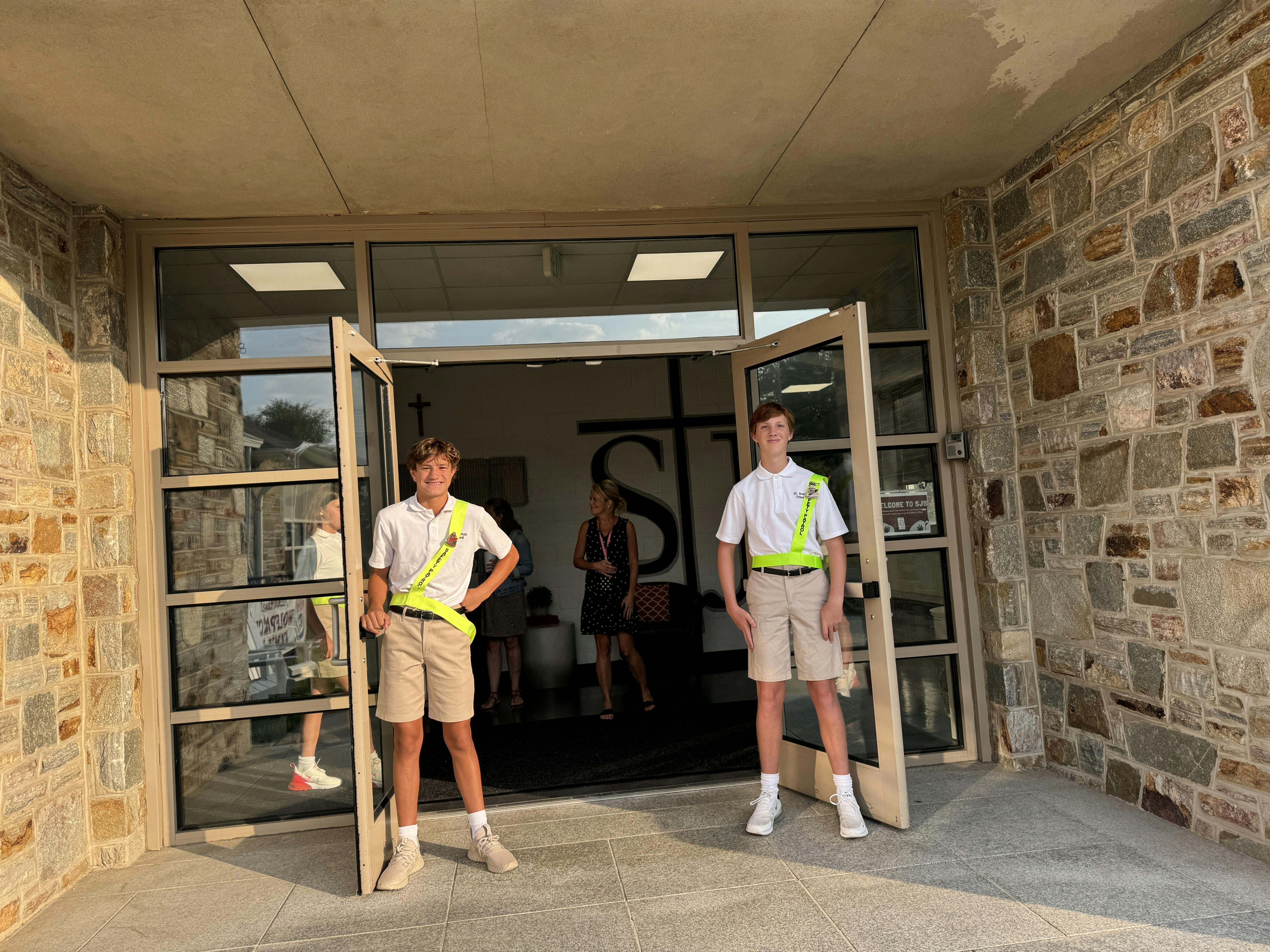 Two teens in uniform with safety vests standing in a doorway