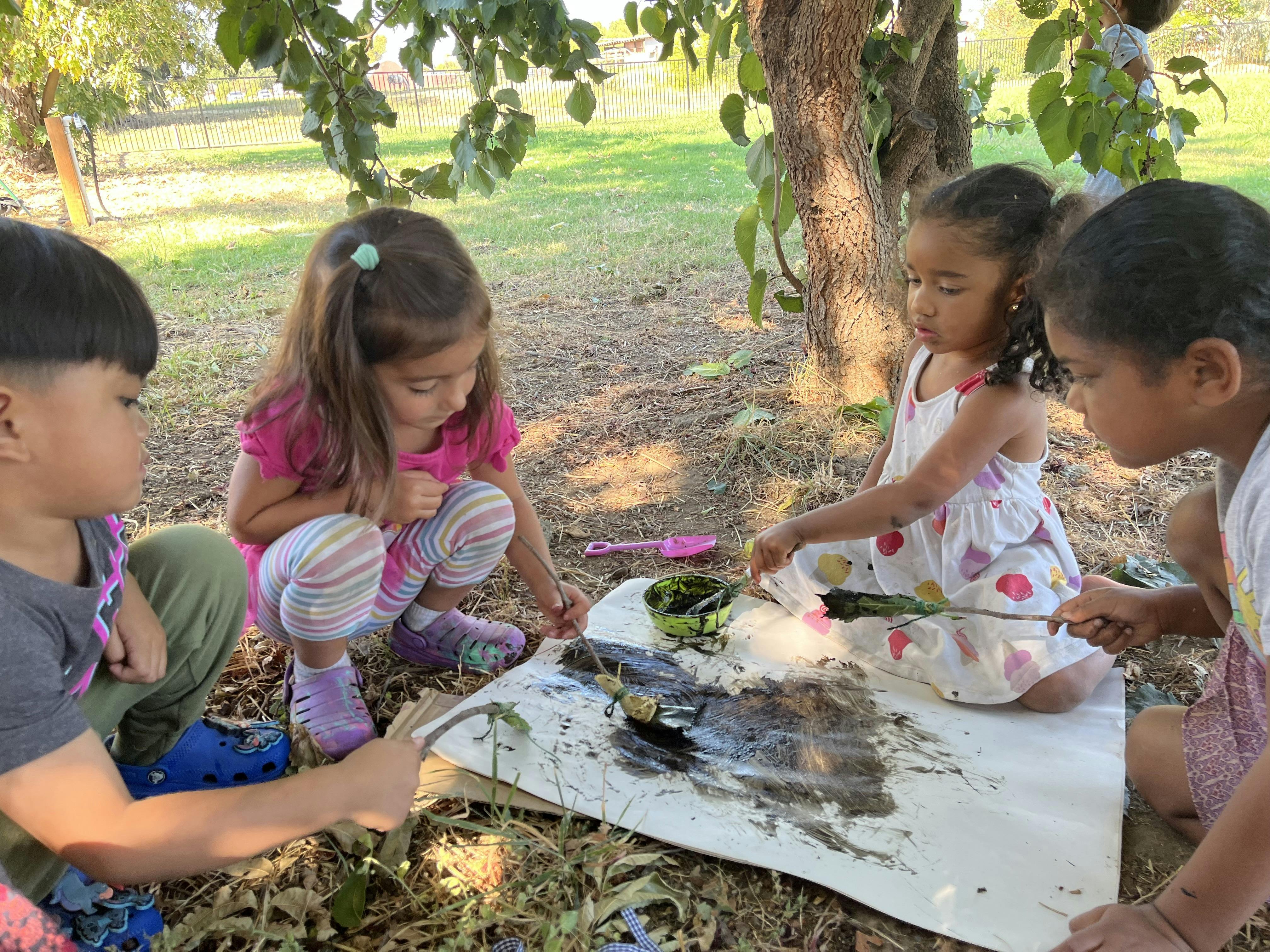 Children painting outdoors on a sheet