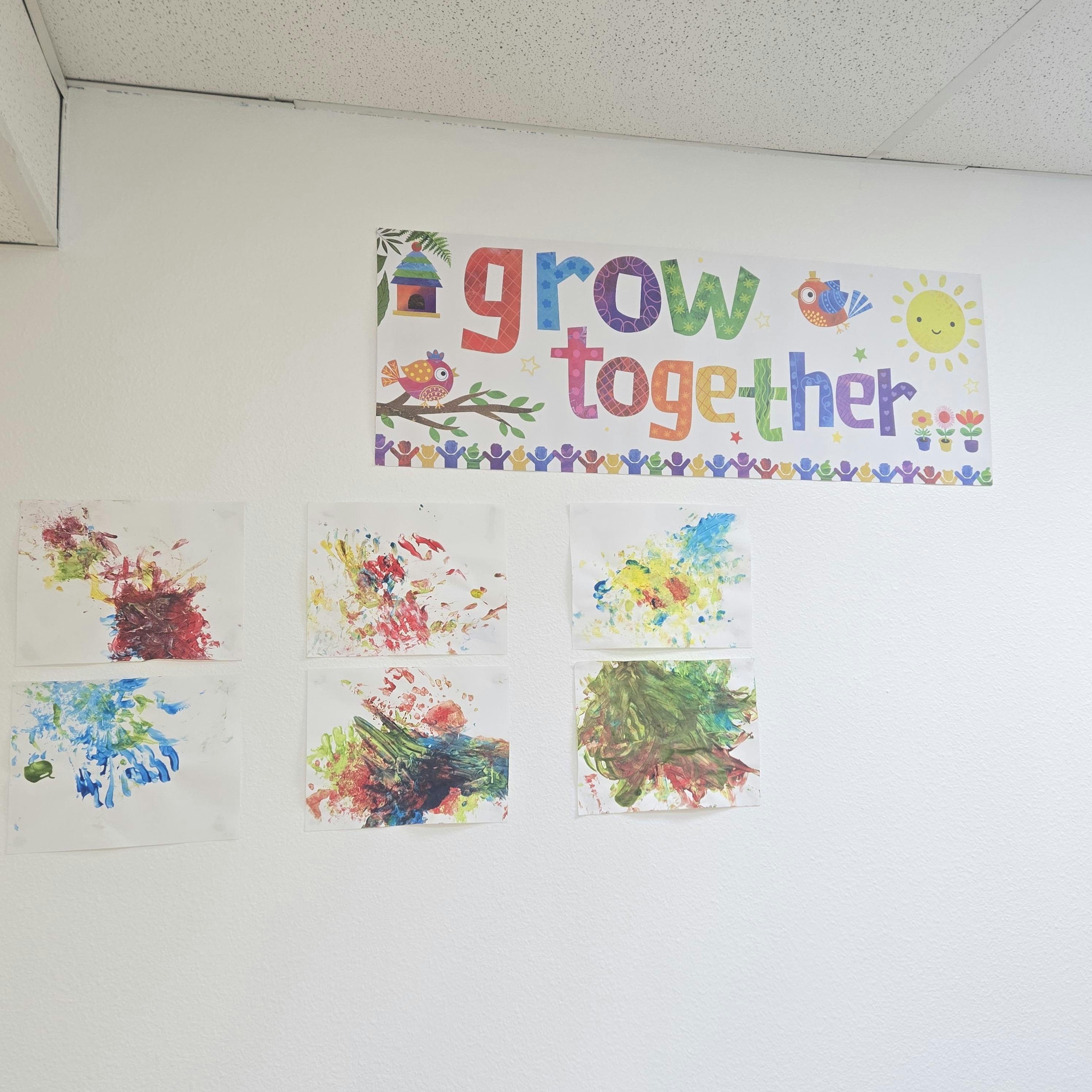 Classroom wall with children's artwork and a "grow together" sign