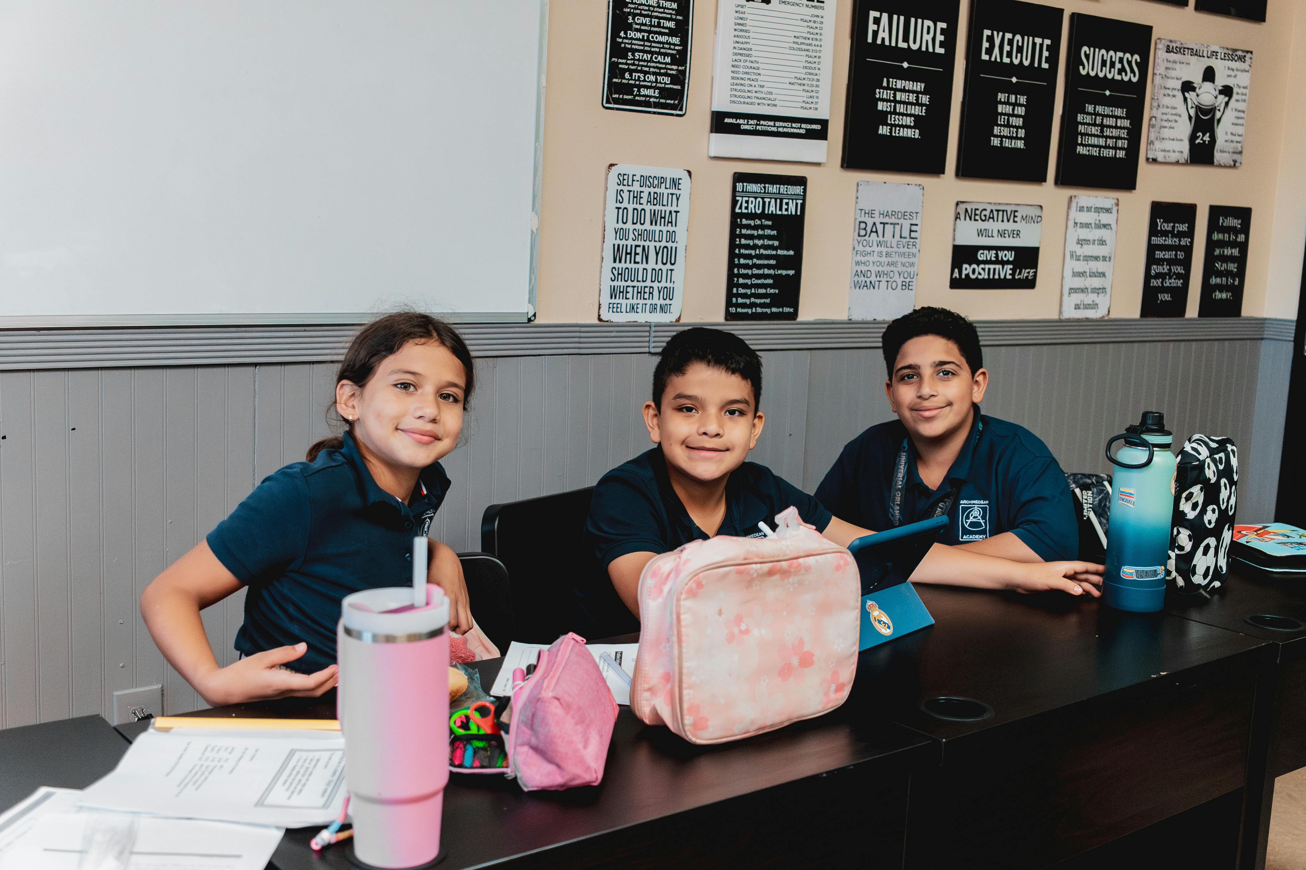 Three children sitting at a desk in a classroom