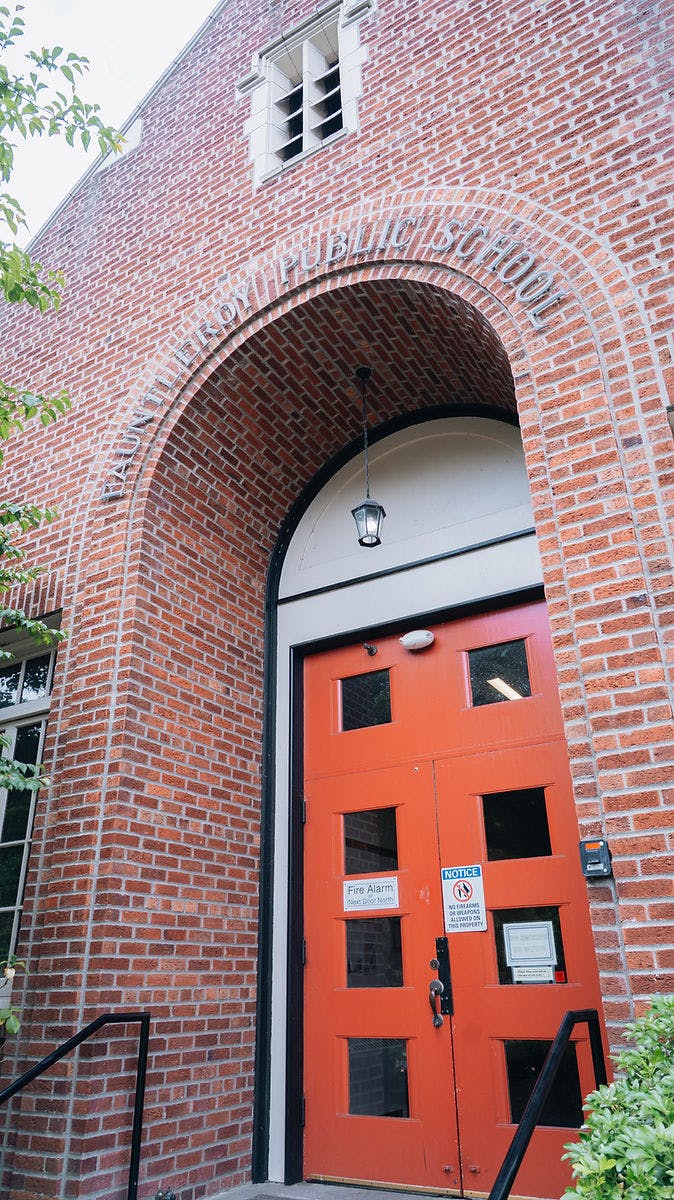 Brick building with arched entryway and red double doors with window panels