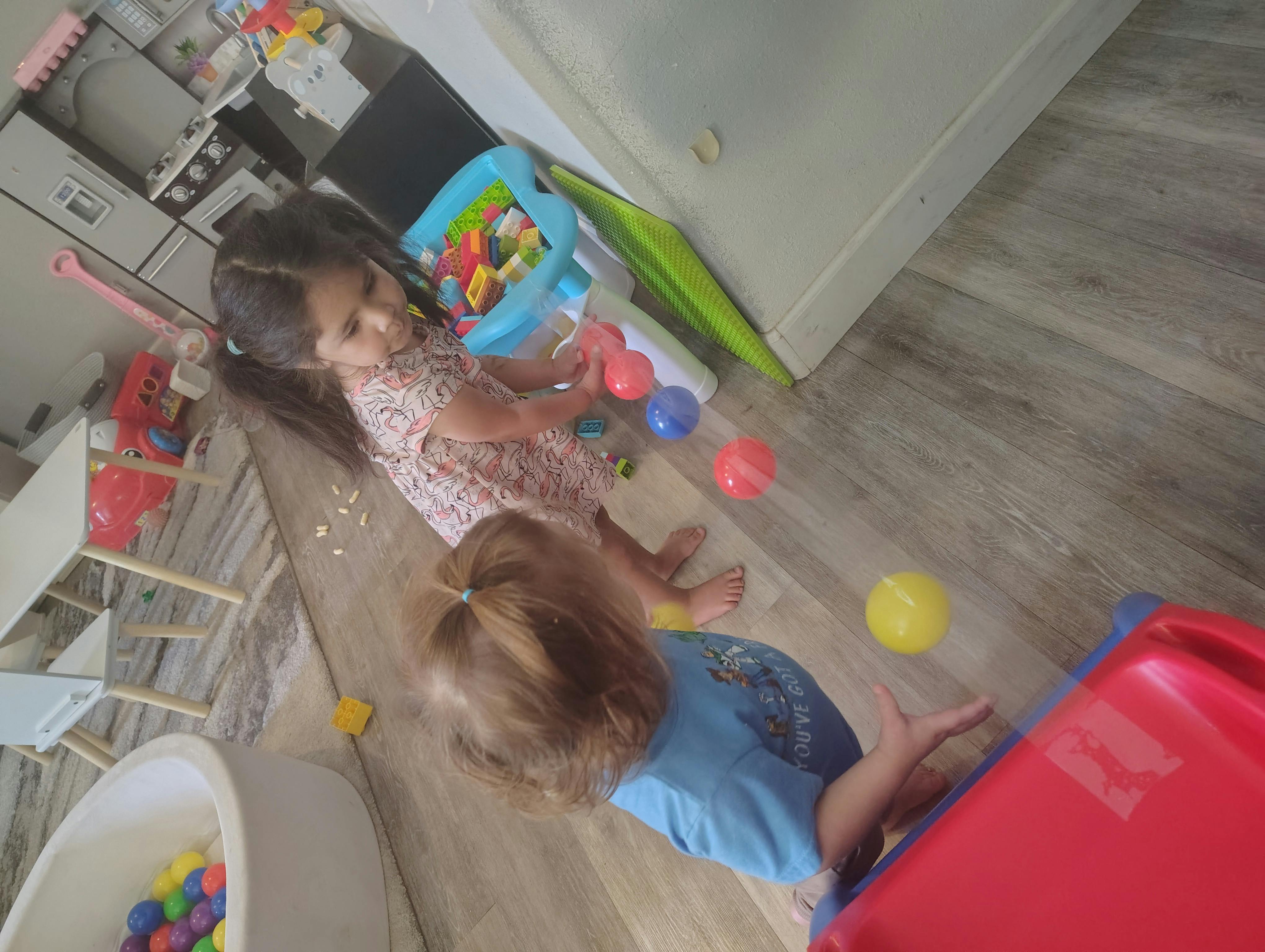 Two children playing with a ball track toy in a playroom