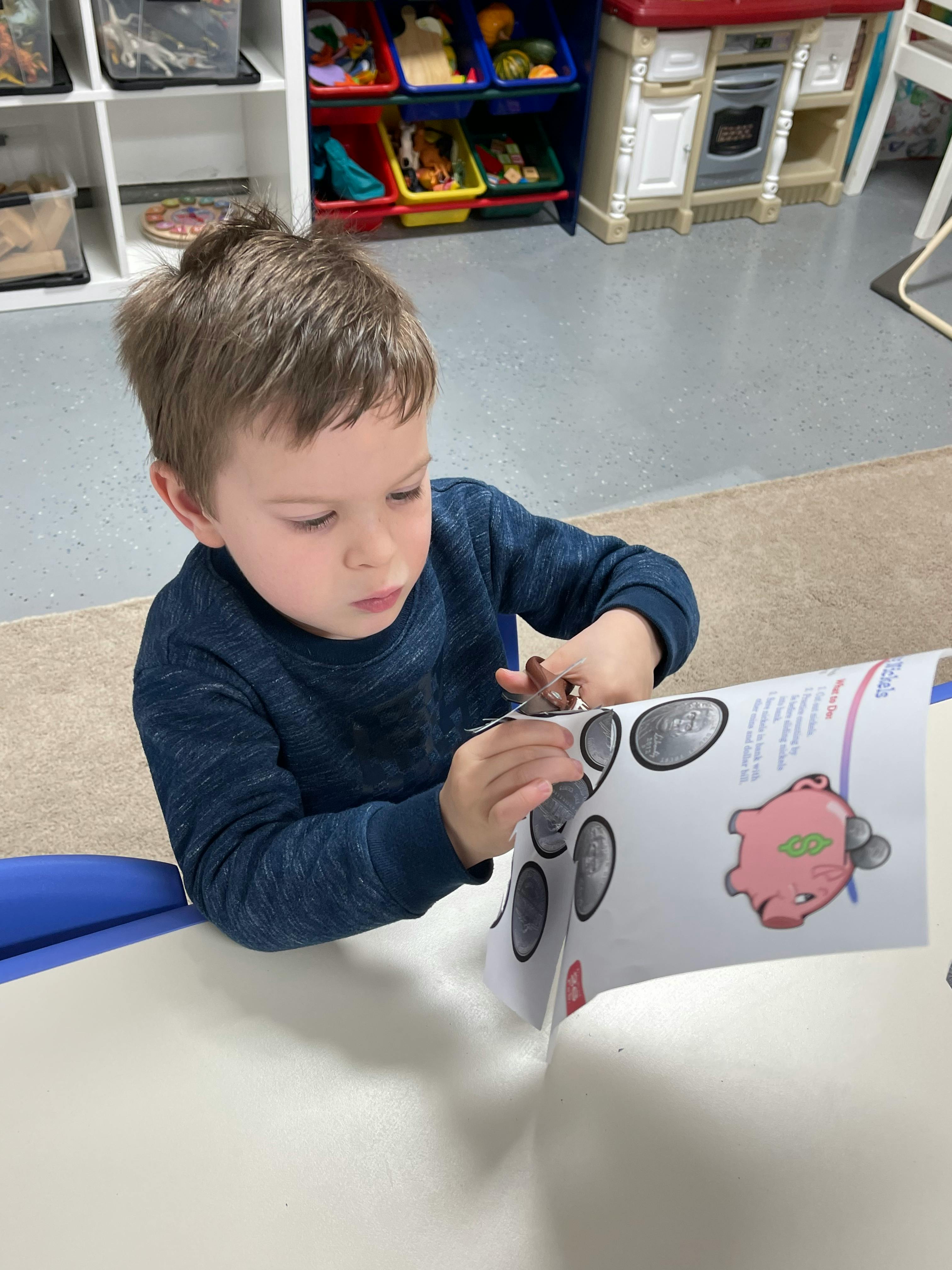 Child cutting out shapes from a paper with scissors