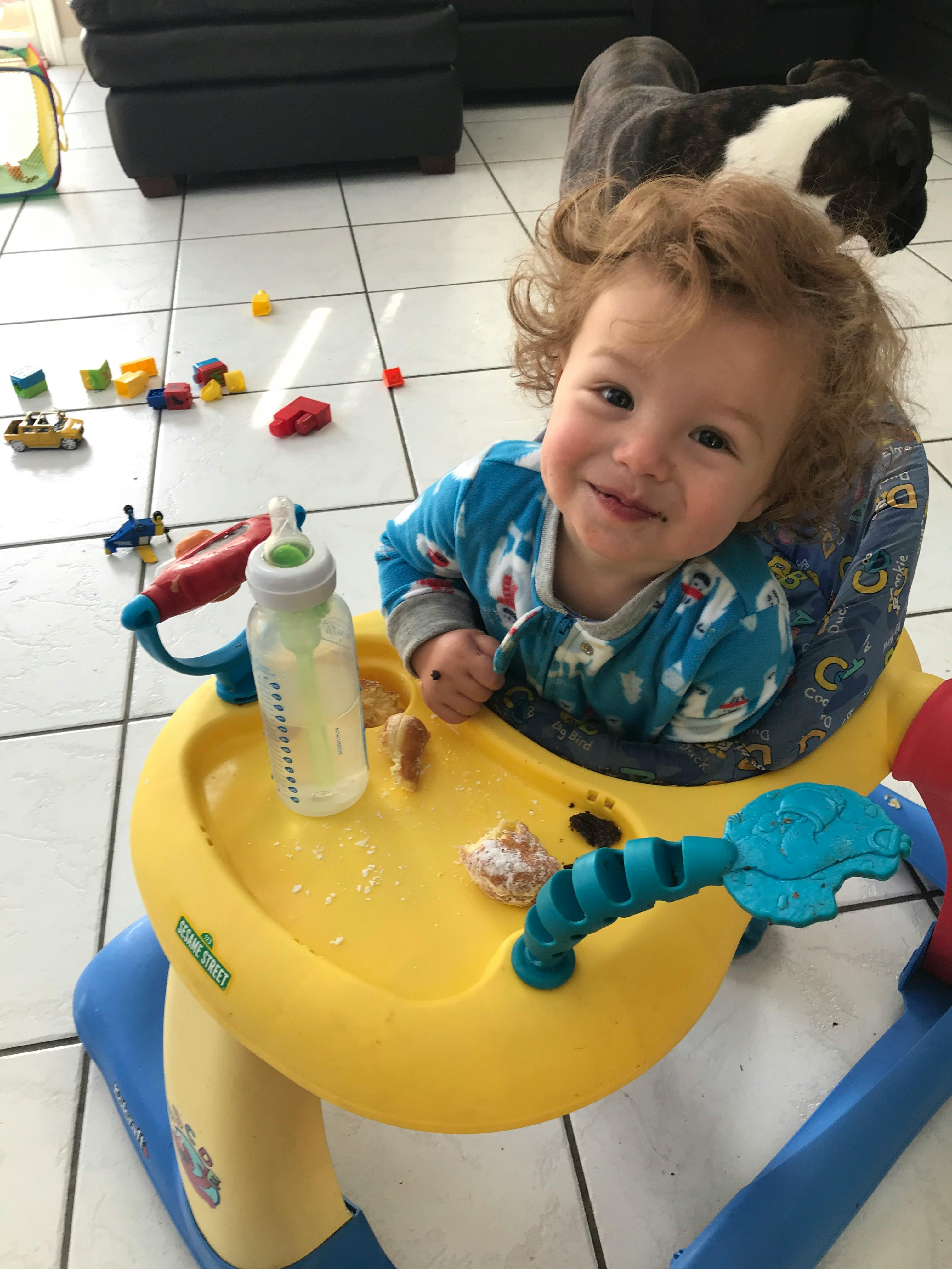 Child in a baby walker with a bottle and snacks