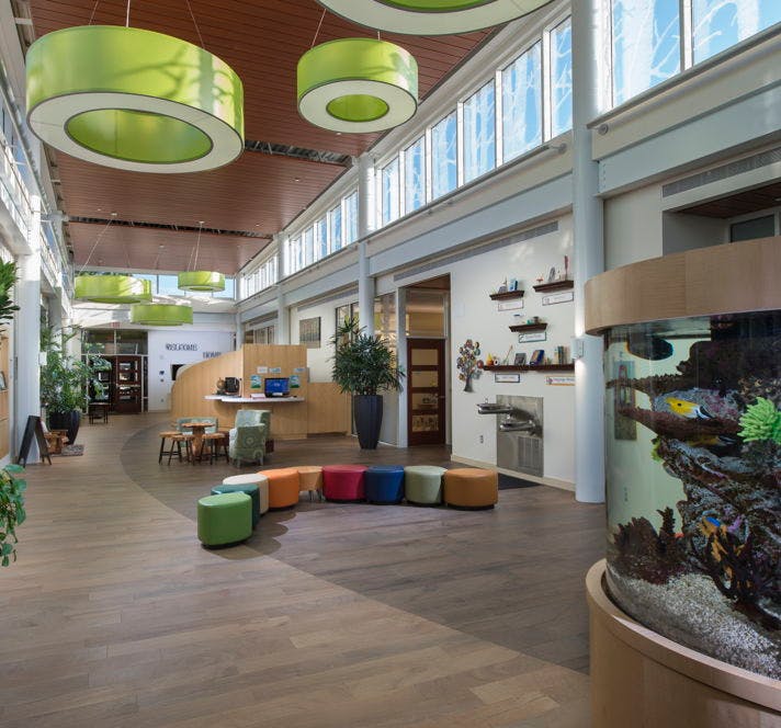 Lobby with colorful seating, a reception desk, and a large aquarium
