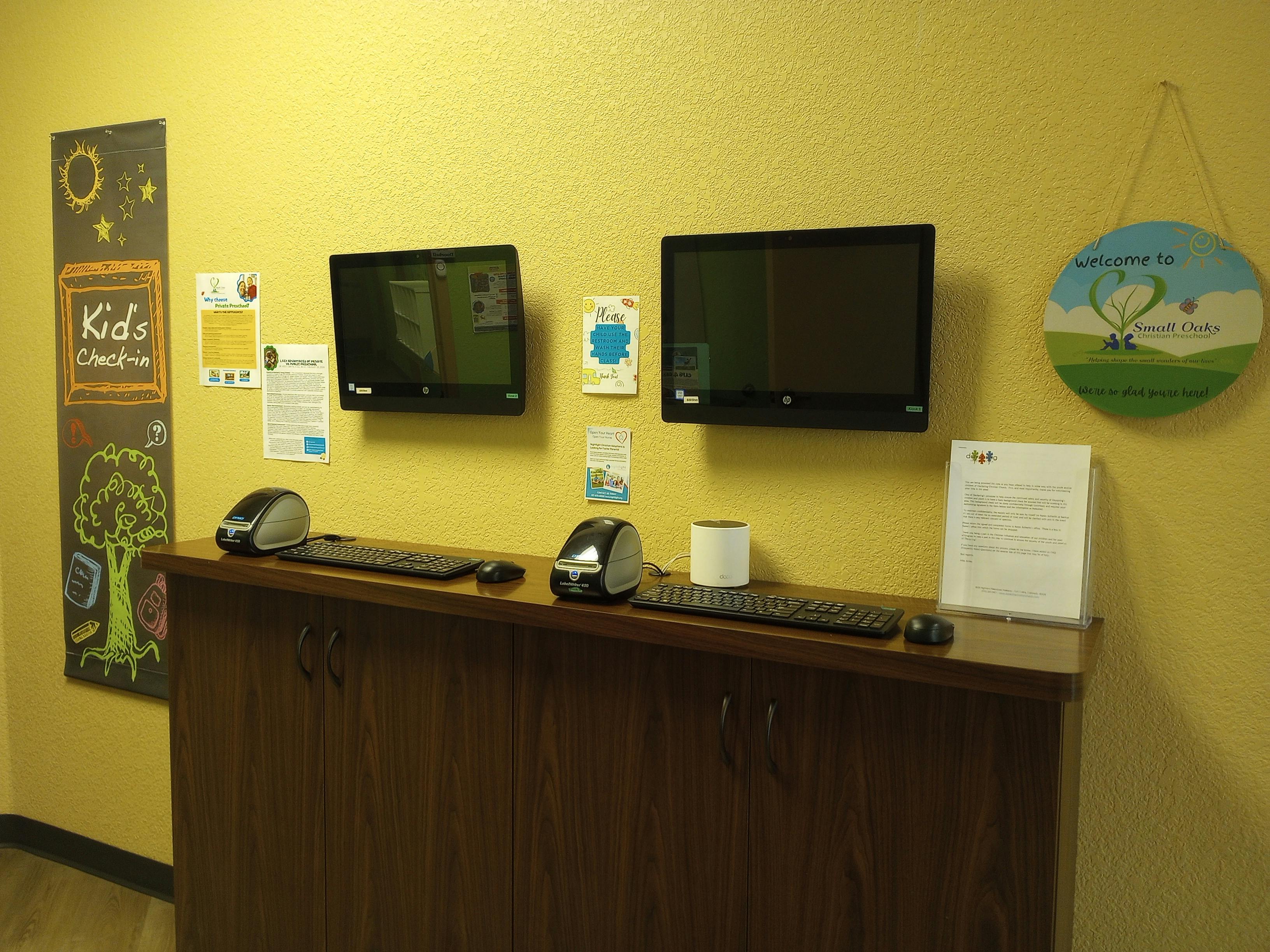 Two computer monitors mounted above a wooden counter with keyboards and mice
