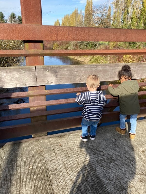Two children looking over a bridge railing at water