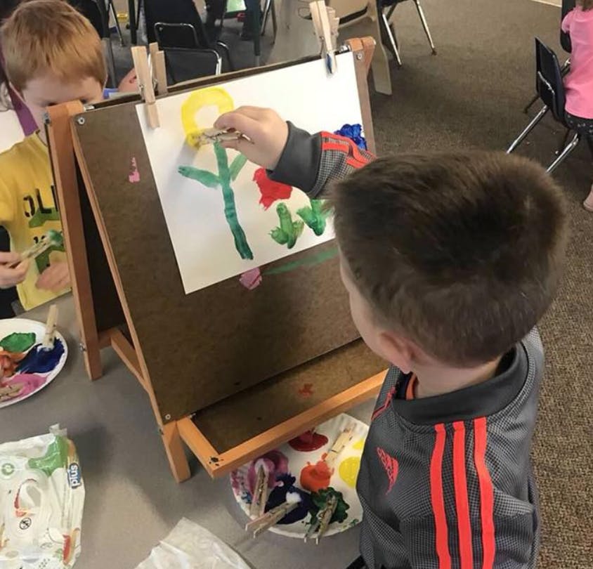 Child painting on an easel in a classroom