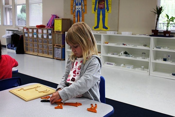 Child playing with a puzzle at a table in a classroom