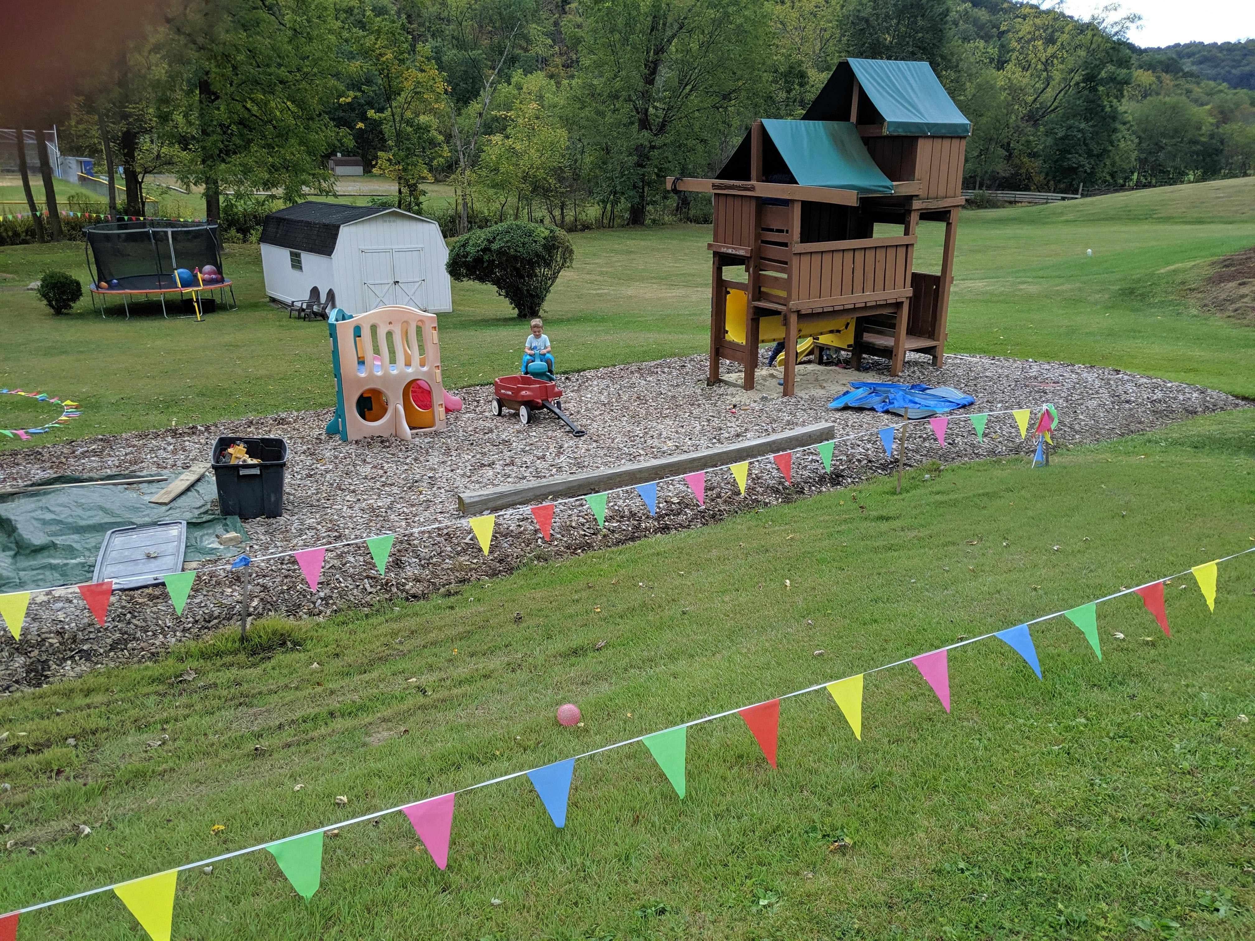 Outdoor play area with a wooden playset, sandbox, and colorful pennant banners