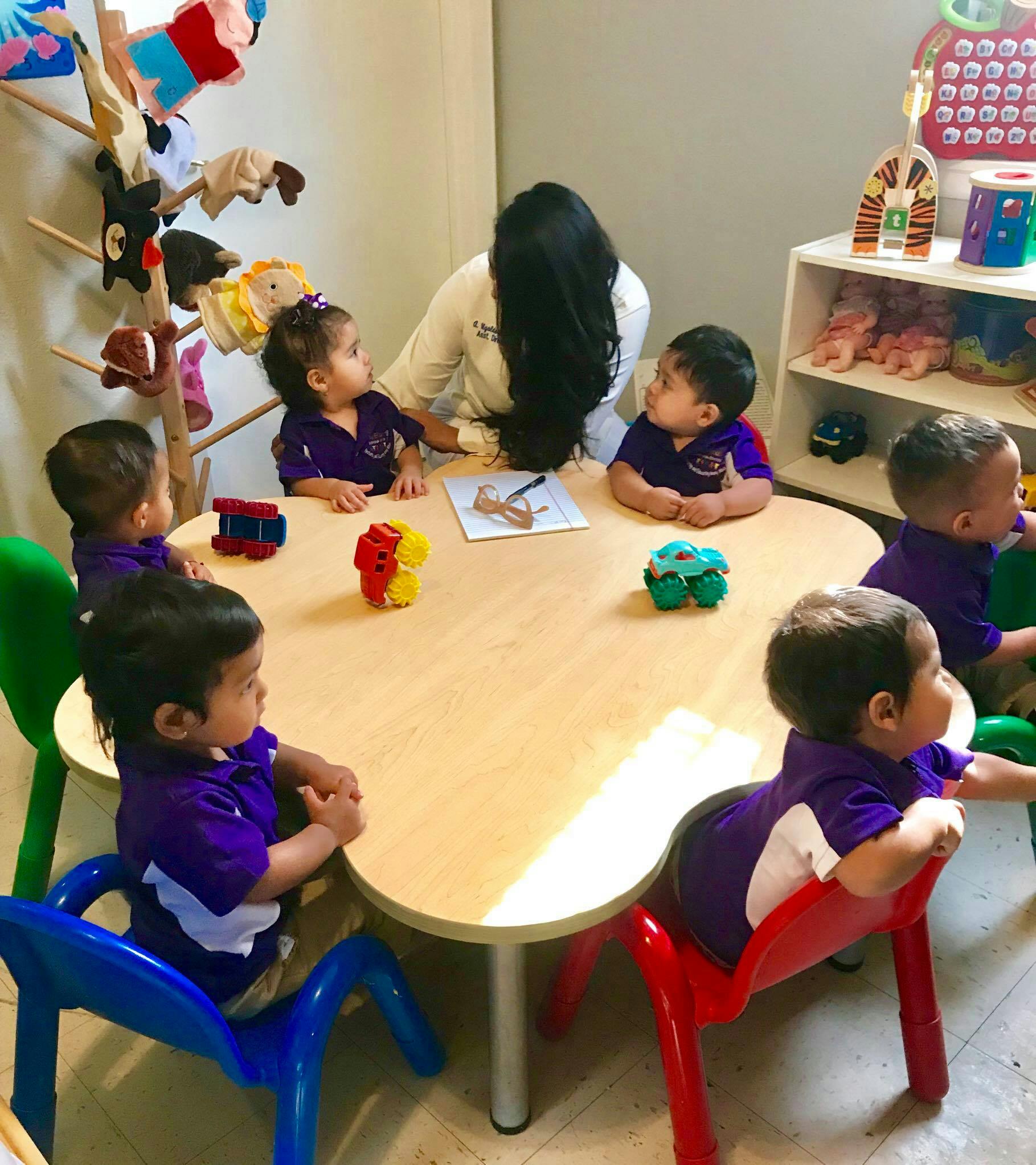 Adult and multiple children sitting around a table in a classroom