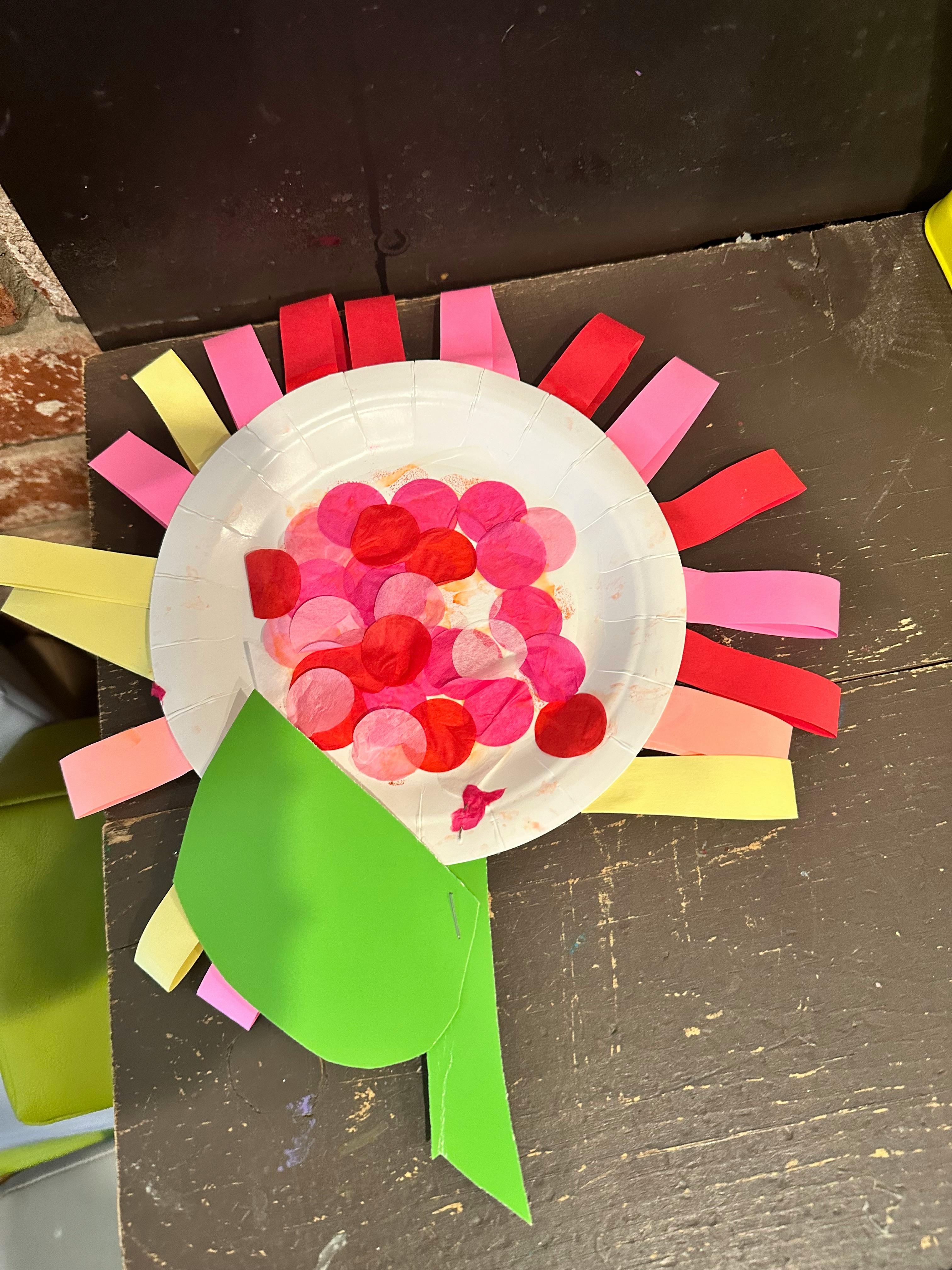 Paper plate craft with colorful paper strips and confetti