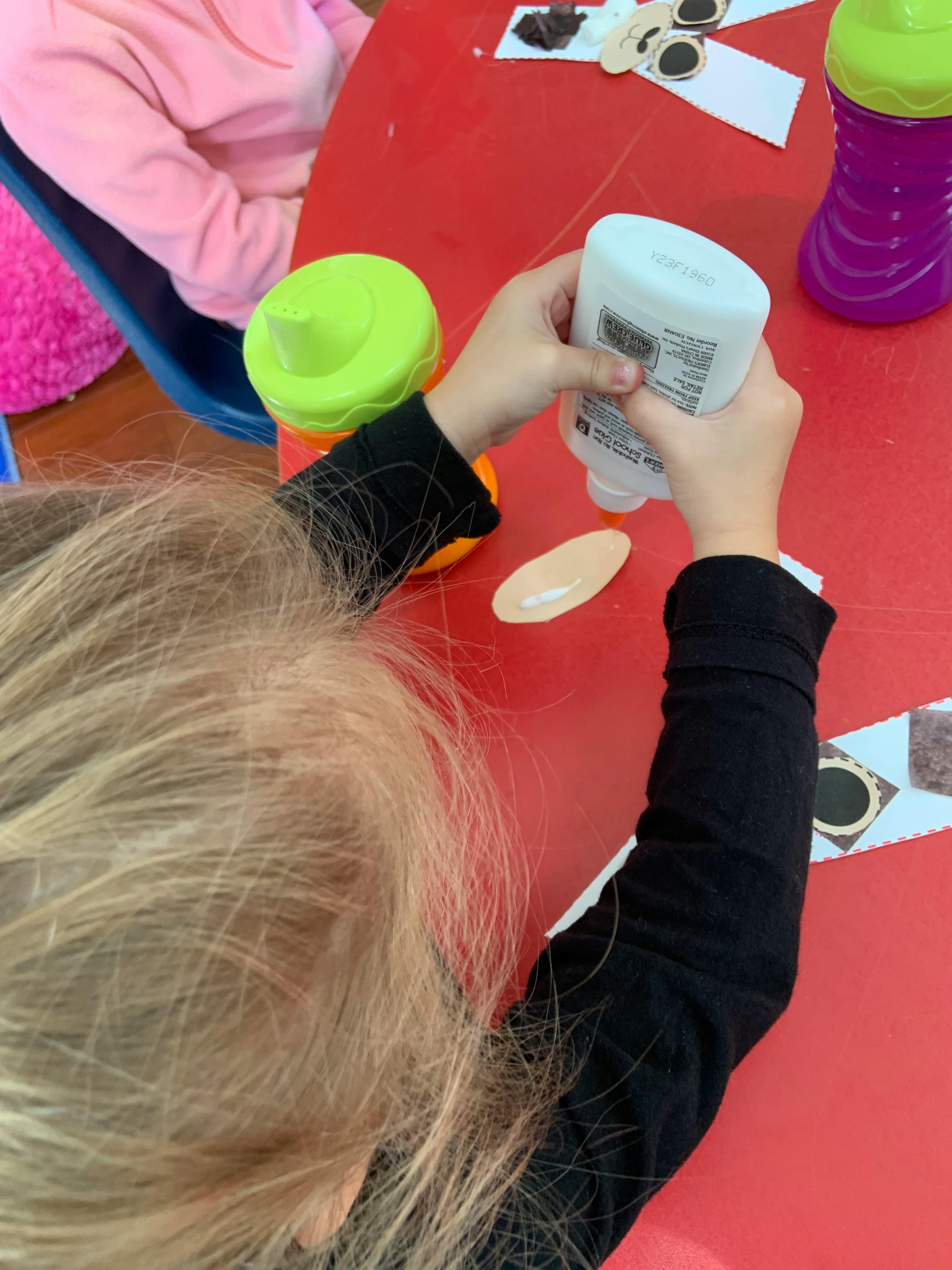 Child squeezing glue onto a piece of paper