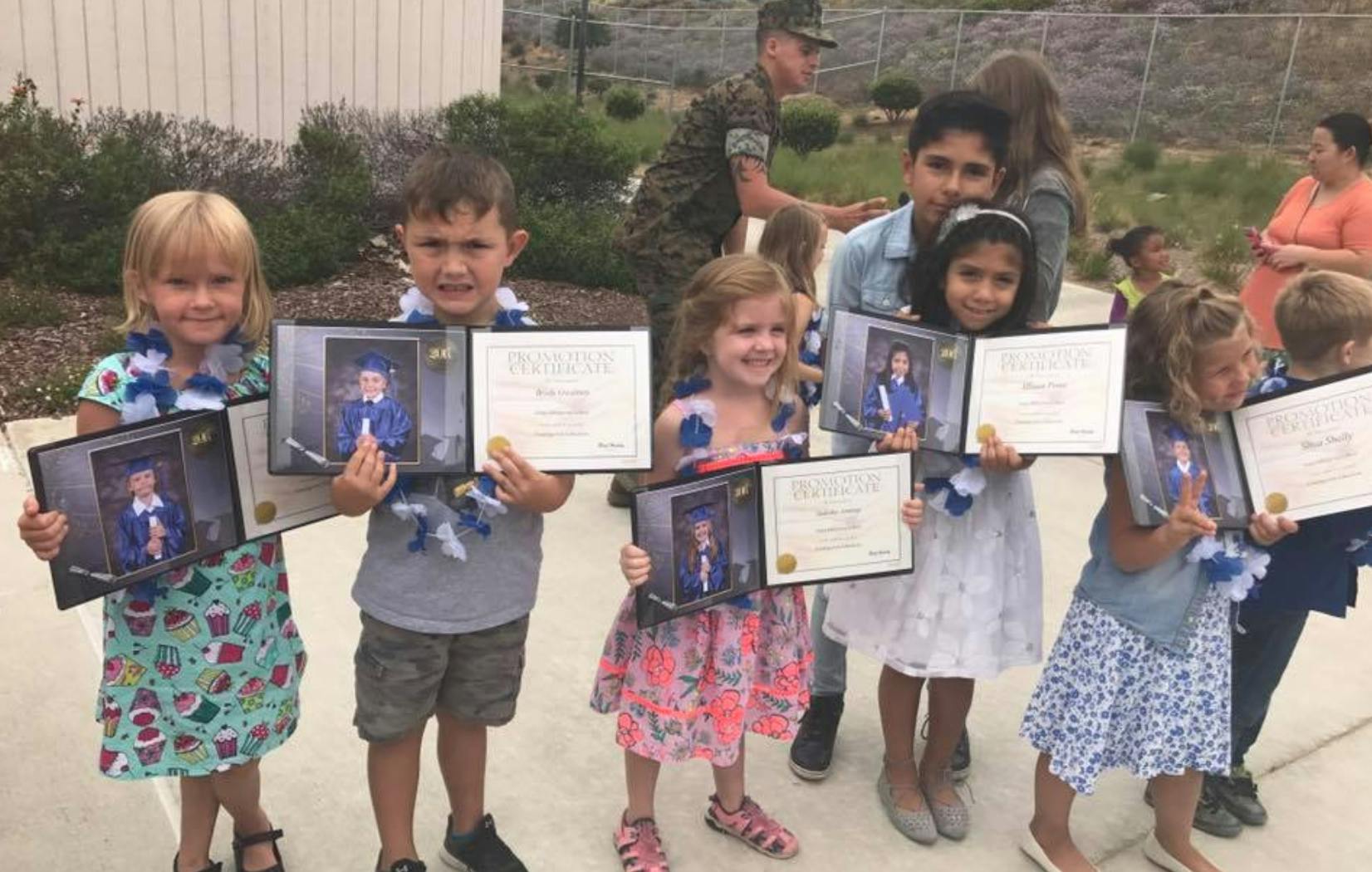 Children holding certificates and framed photos