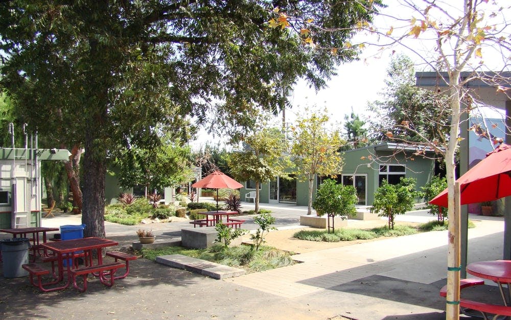 Outdoor area with picnic tables, trees, and buildings