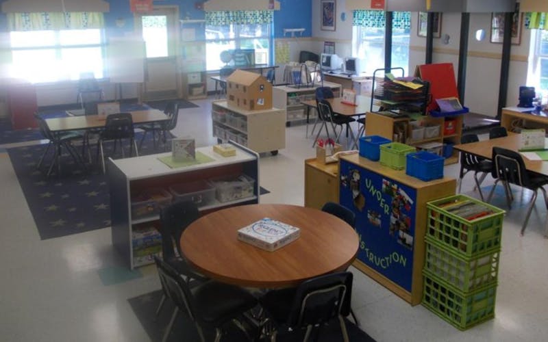 Classroom with multiple tables and chairs, storage units, and a board game on a round table