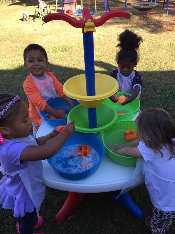 Four children playing with a water table outdoors