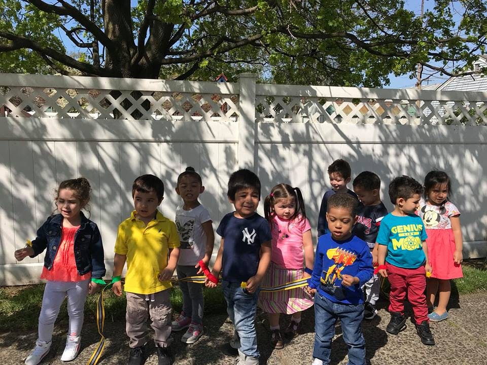 Group of children standing in front of a white fence