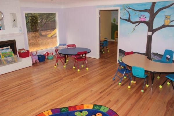 Classroom with small tables and chairs, tree mural on wall