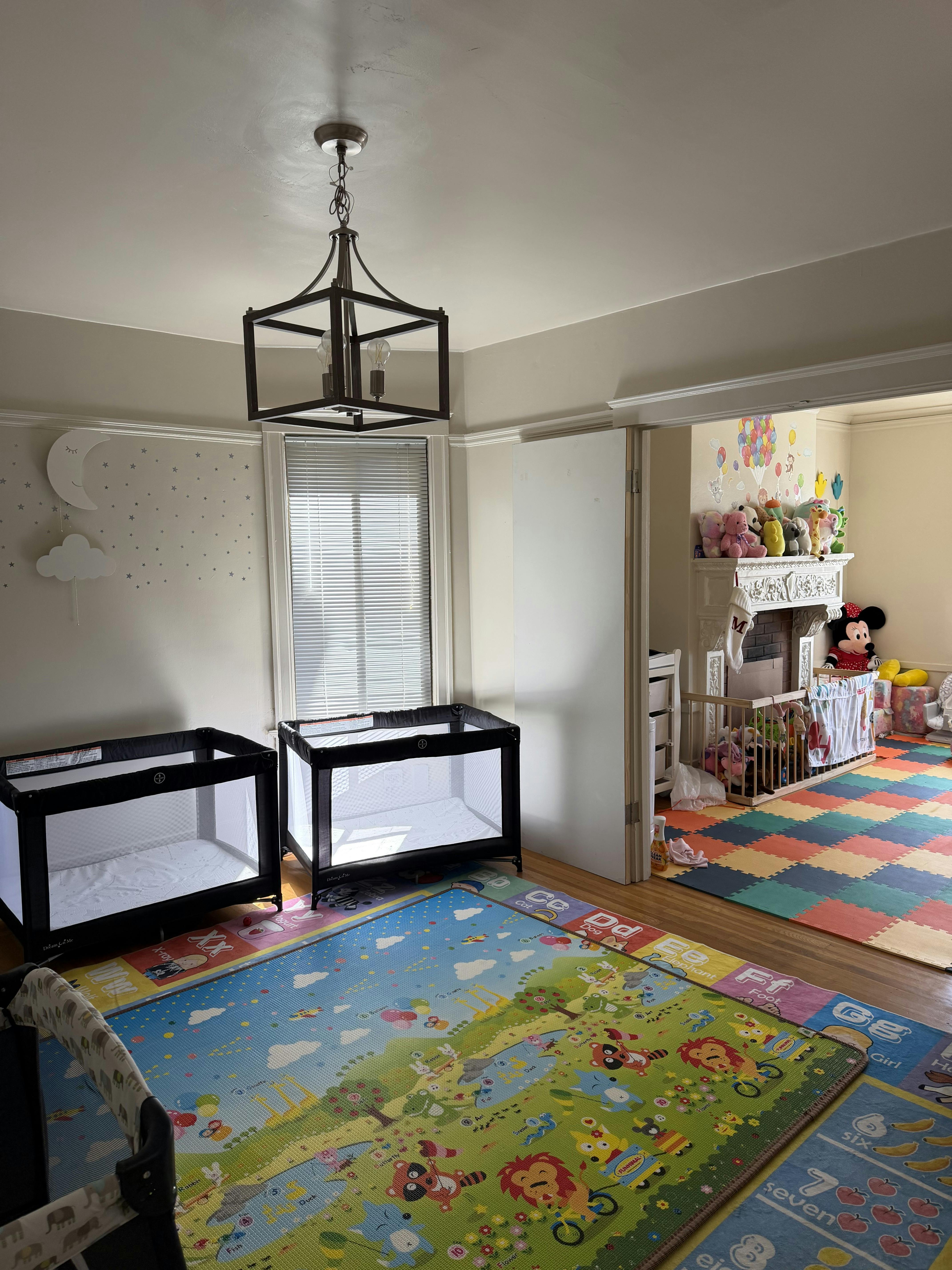 baby and toddler play area with cribs, play mats, and a stuffed animal collection