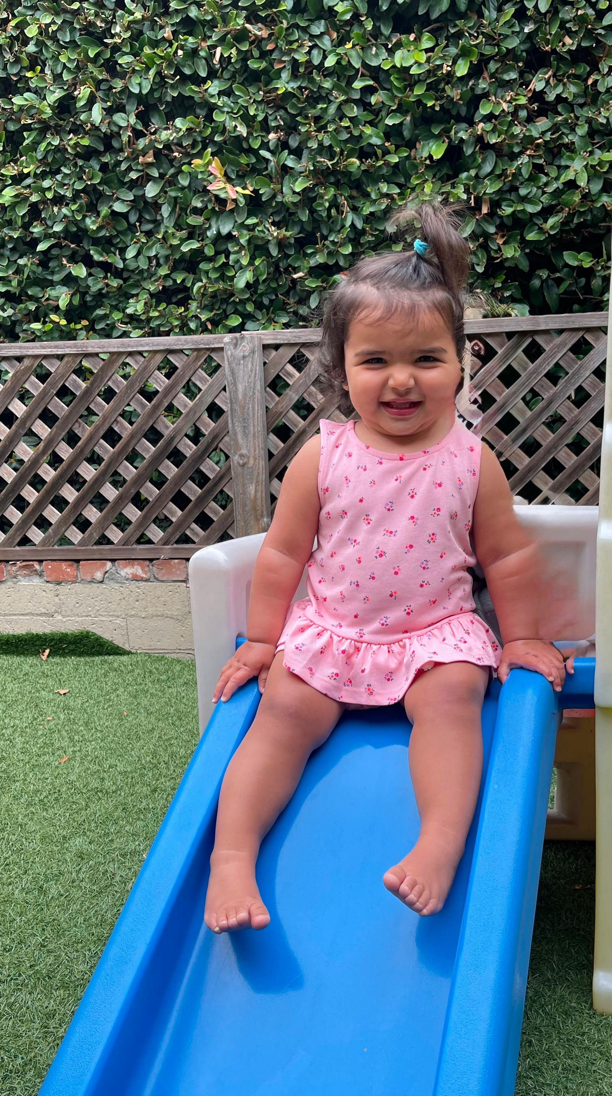 Child sitting on a slide in a yard