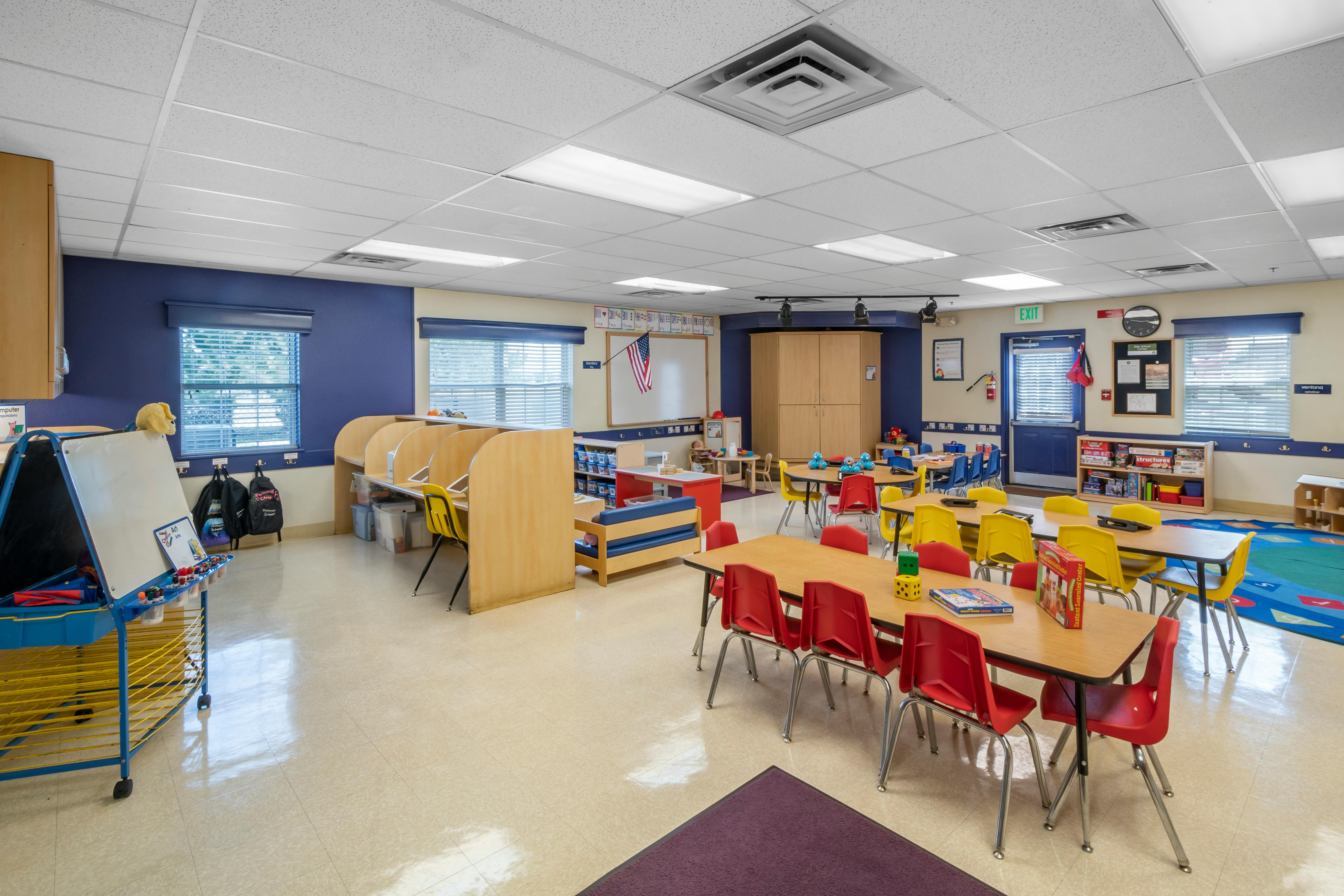 Empty colorful preschool classroom with tables and chairs