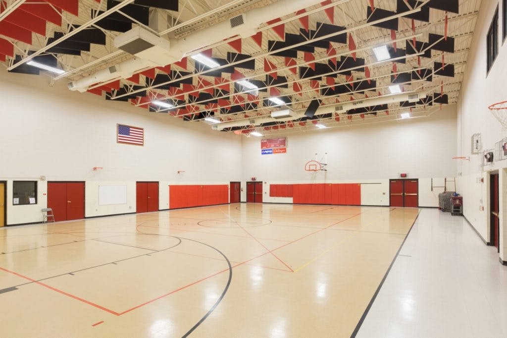 Empty gymnasium with a basketball court and American flags on the wall
