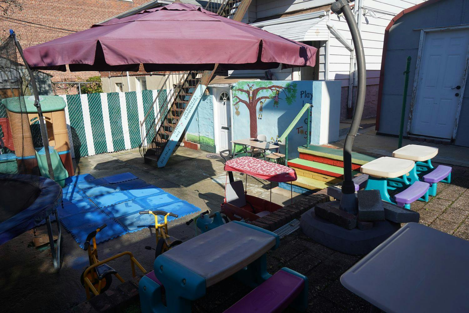 Outdoor play area with a large umbrella, slide, and small tables