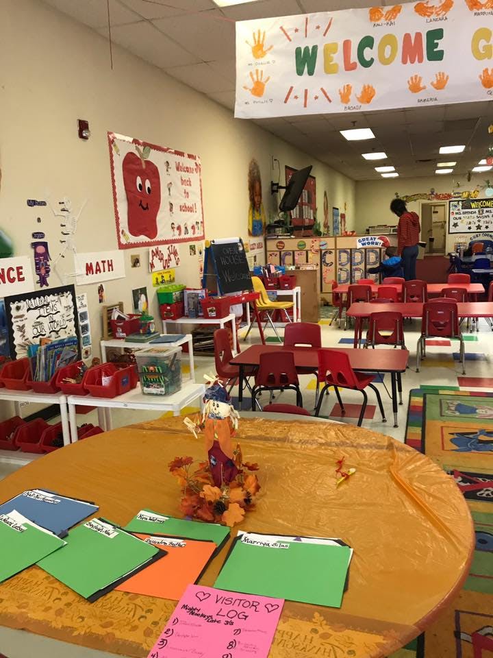 Classroom with a welcome banner, tables, chairs, and a person standing