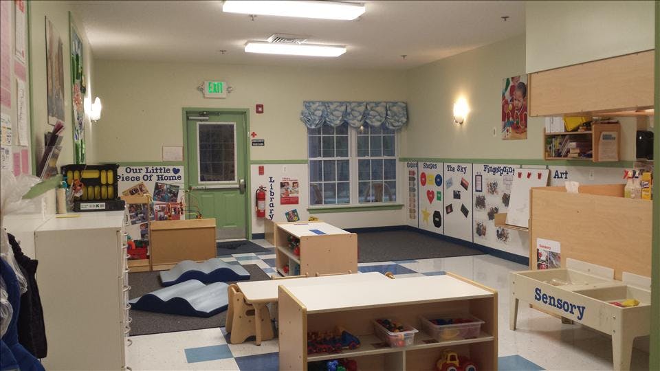 Classroom with tables, shelves, windows, and an exit sign