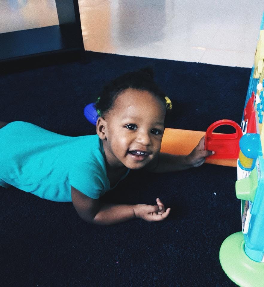 Child lying on stomach on floor, looking at camera