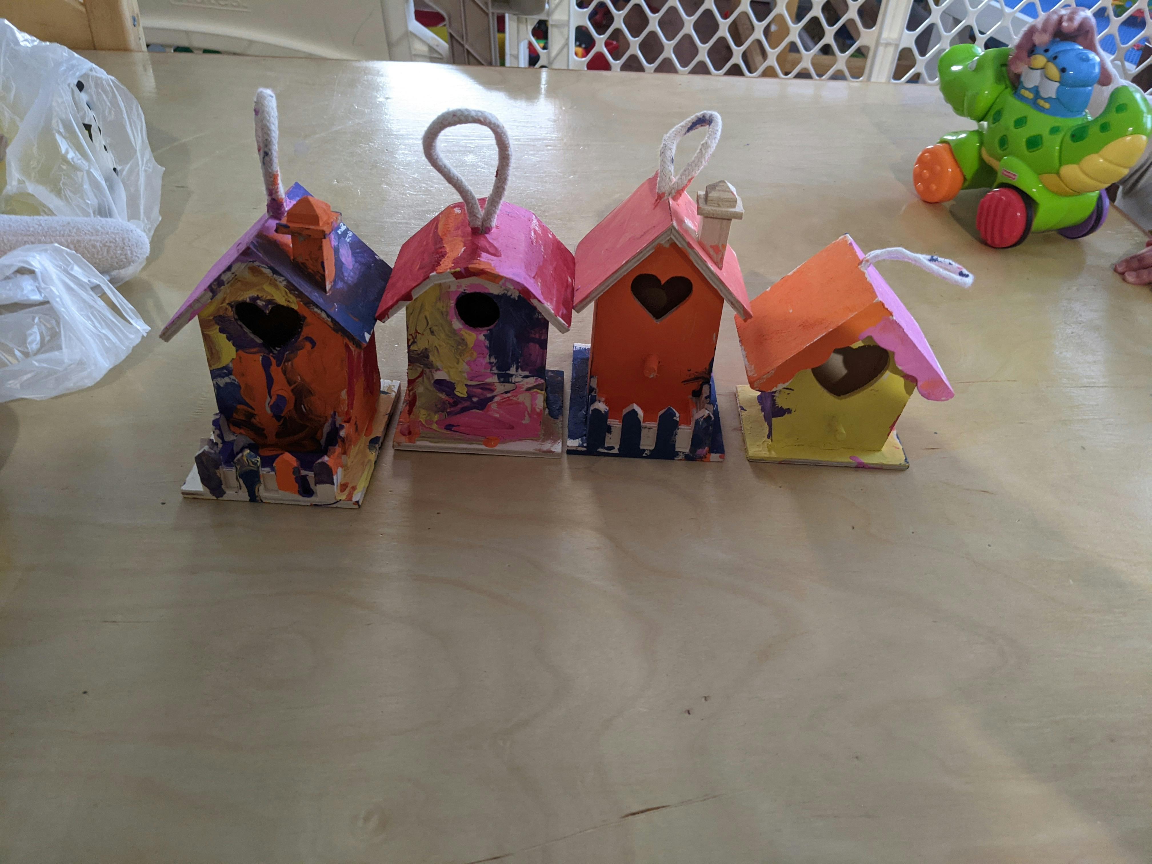 Four colorful, painted birdhouses with string hangers