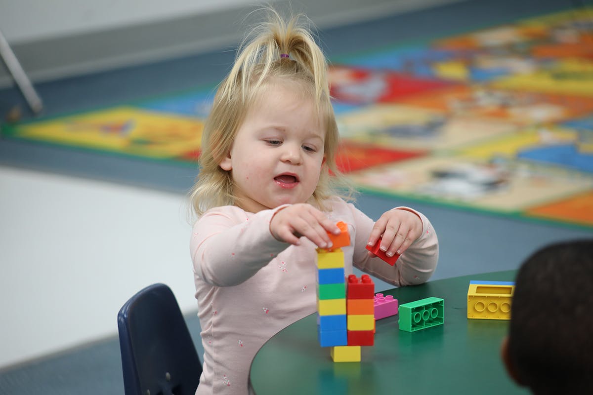 Child playing with colorful building blocks at a table
