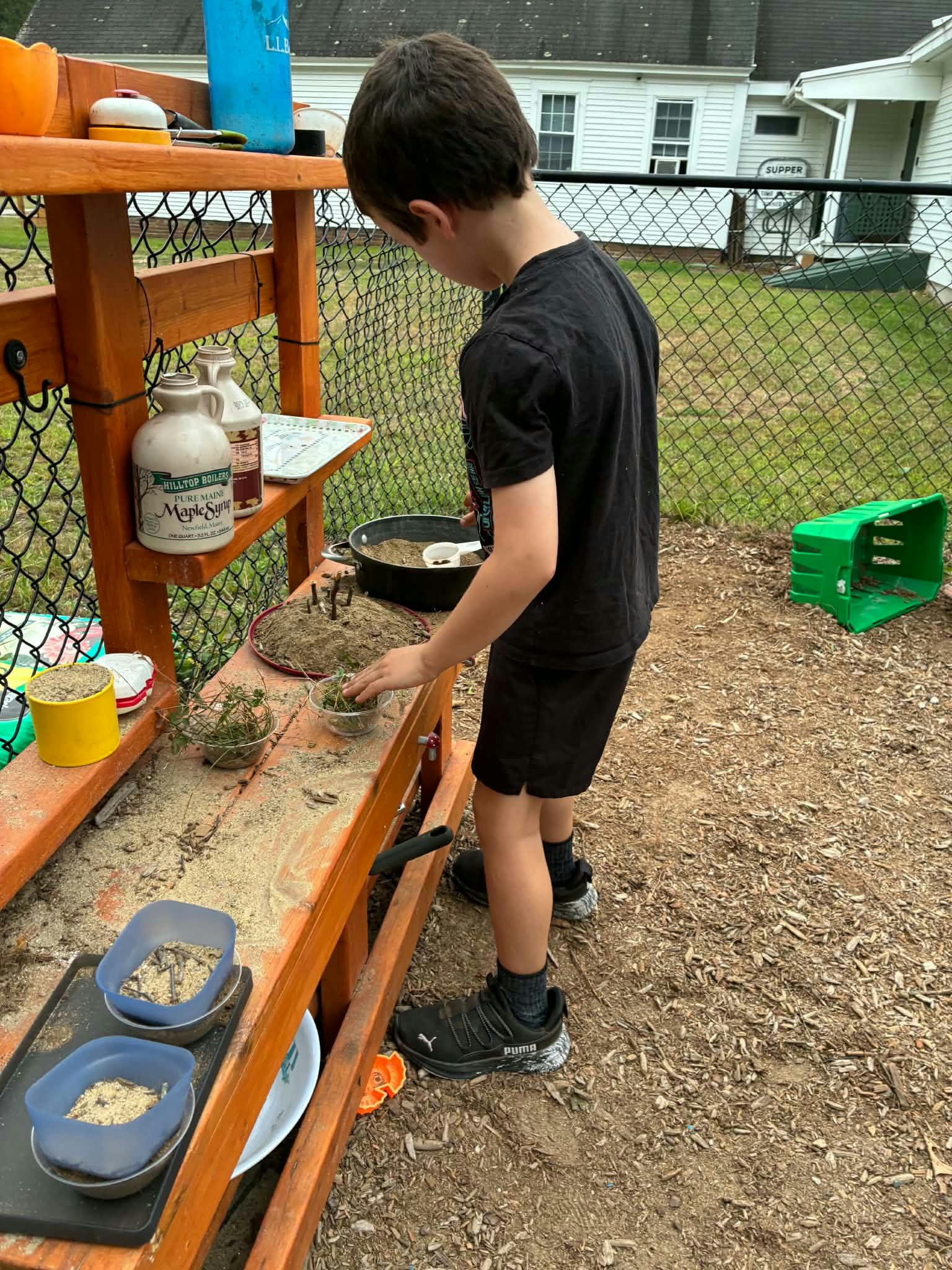 Child playing at an outdoor mud kitchen